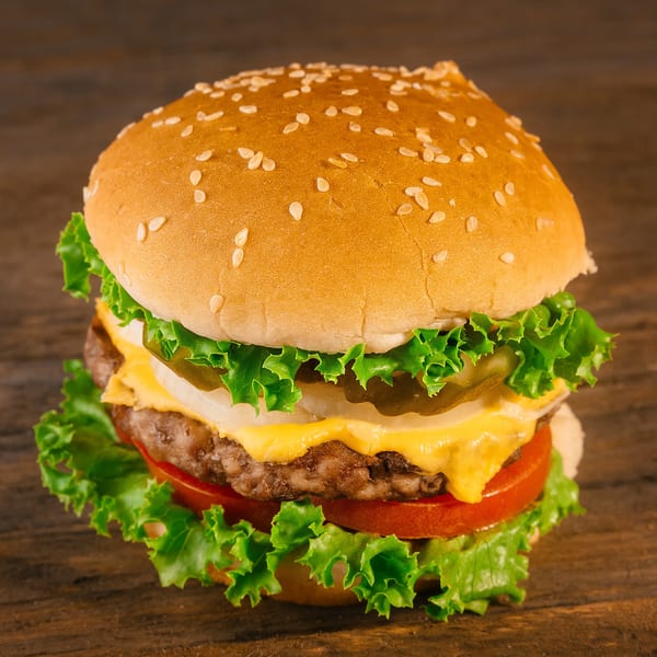 A Sail N' Power Grill cheeseburger with lettuce, tomato, onion, and pickles on a sesame seed bun.